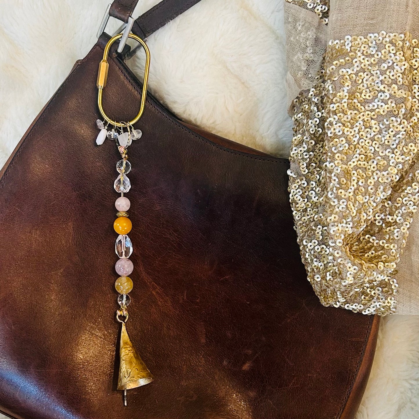 Spirital bell charm styled as bagd charm with brass carabiner with gemstone accents.