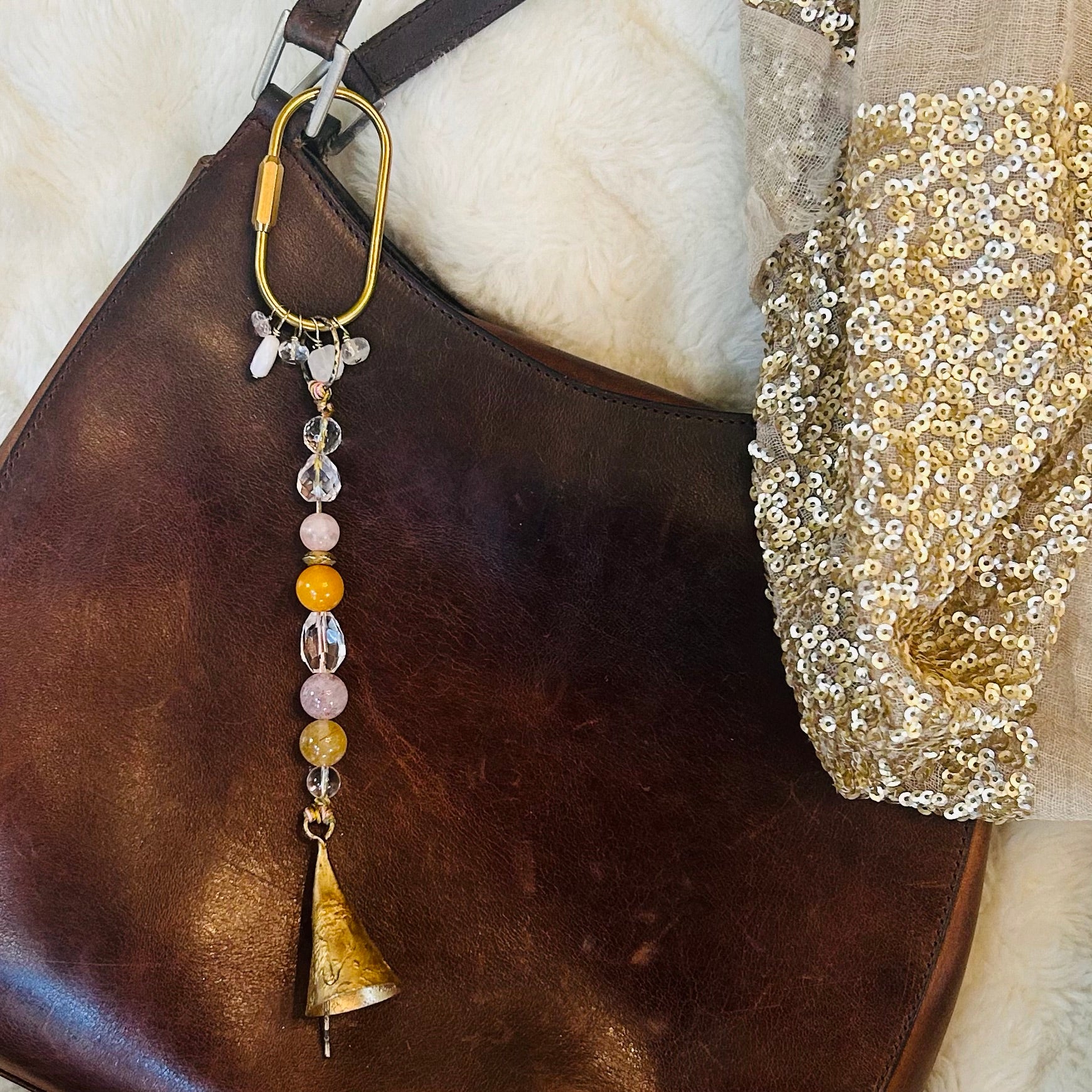 Spirital bell charm styled as bagd charm with brass carabiner with gemstone accents.